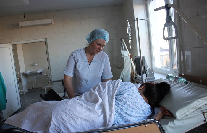 Дежурная акушерка Светлана Фролова в родильном блоке оказывает помощь матери при кормлении ребёнка.
